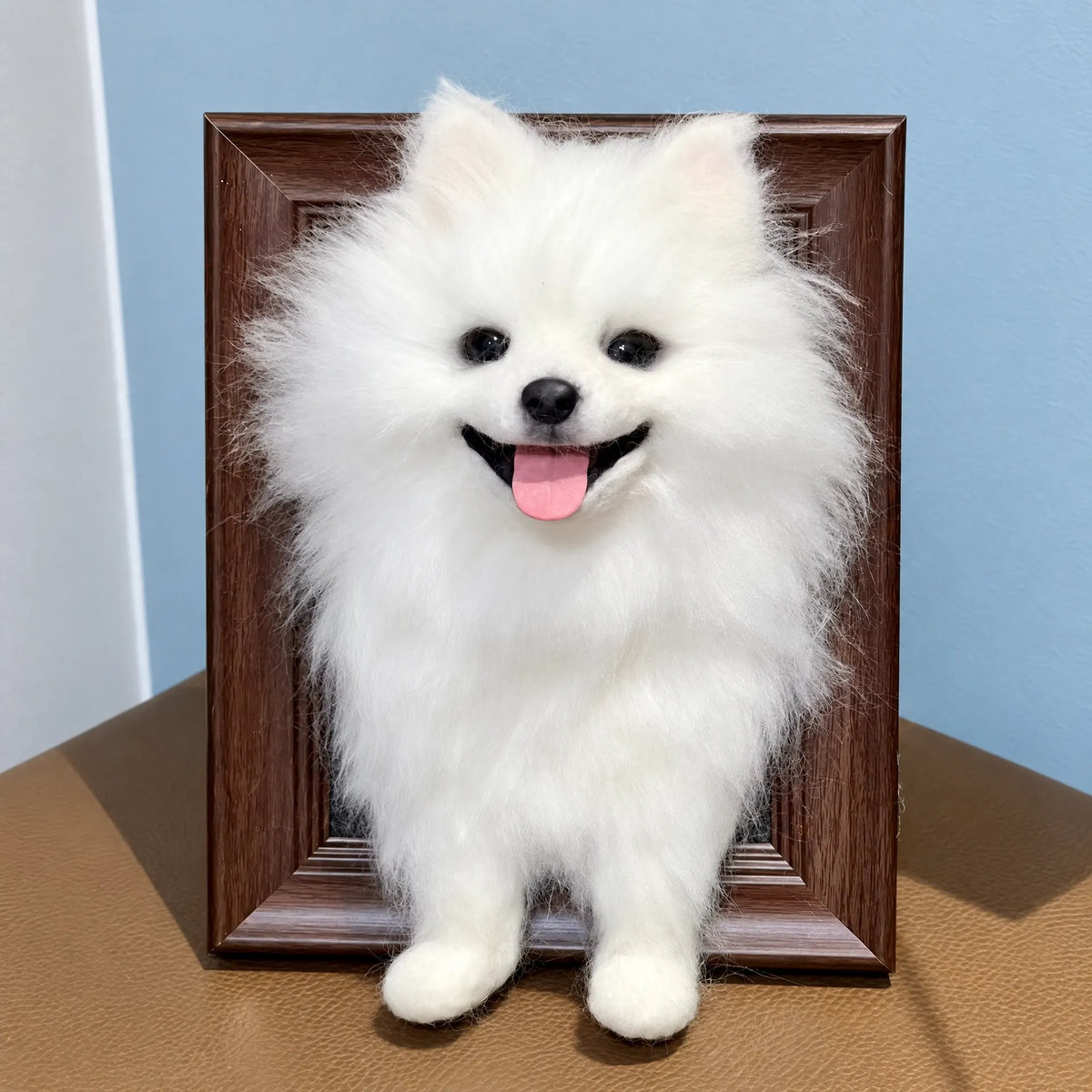 Framed needle-felted white dog portrait against a light blue background